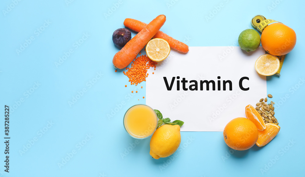 Paper sheet with text VITAMIN C and fresh products on color background