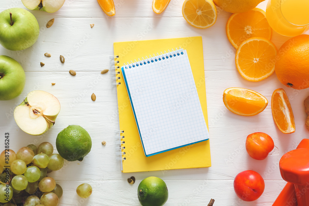 Fresh products with notebooks on white wooden background. Diet concept