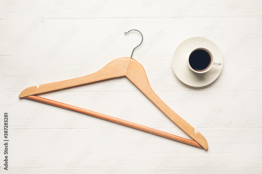 Clothes hanger and coffee on white wooden background