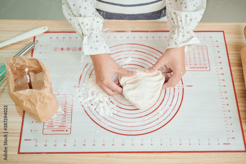 Hands preparing bread dough on wooden table.