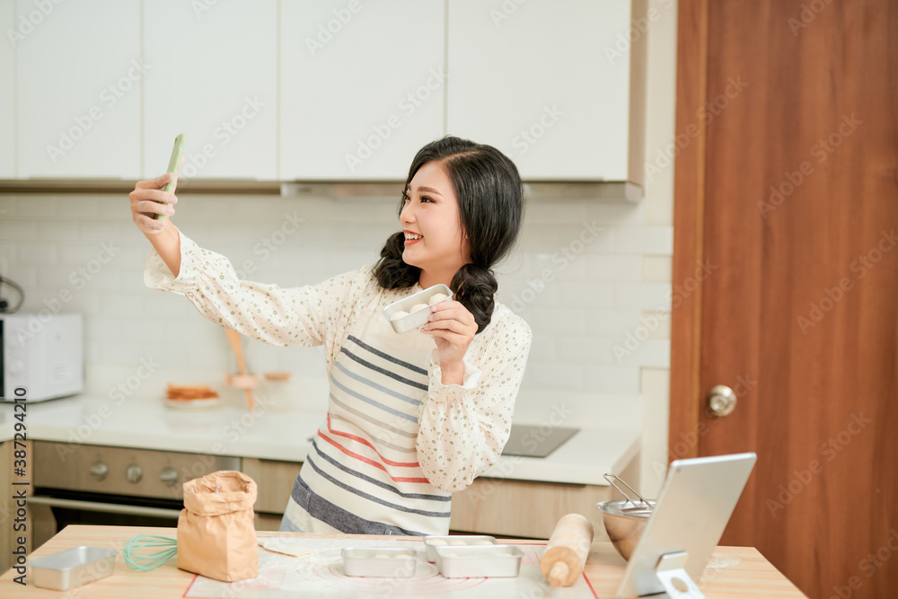 美丽的女人在烤盘上用新鲜的生蛋糕面糊拍照，女人的手涂着面粉