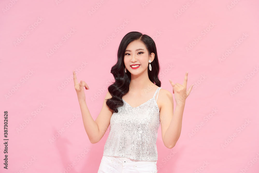 female posing in long silver party dress over pink background