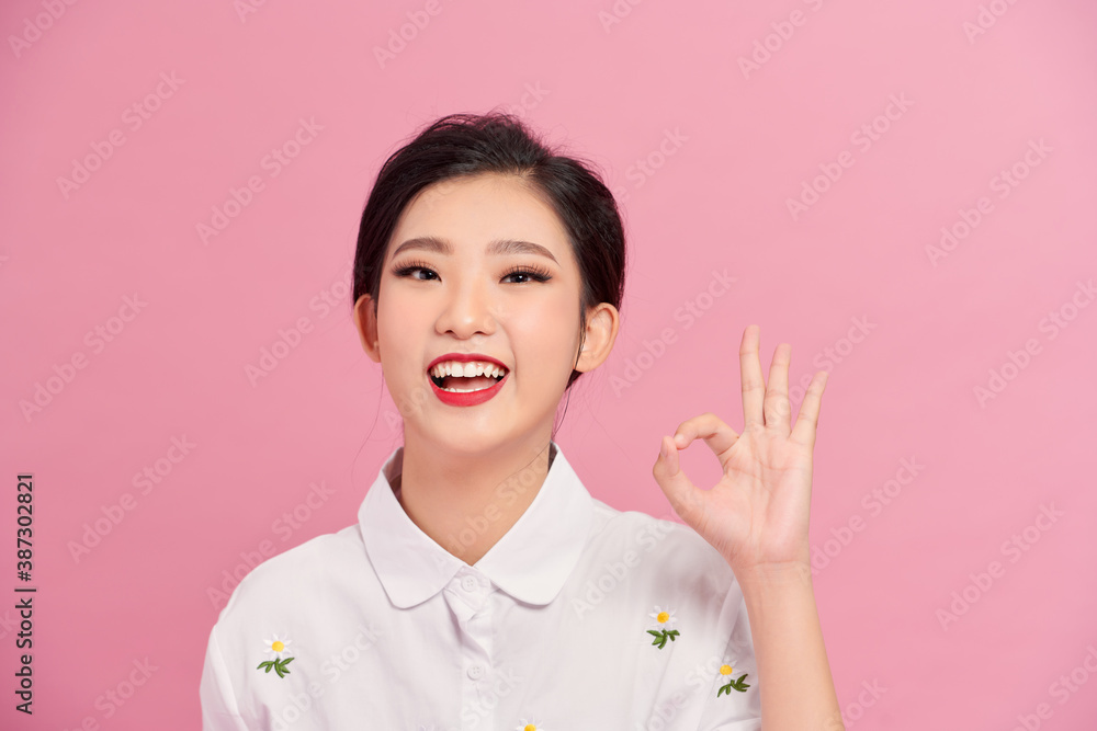 beautiful model, showing OK, thumbs up, with her fingers, isolated on white, smiling. Asian young wo