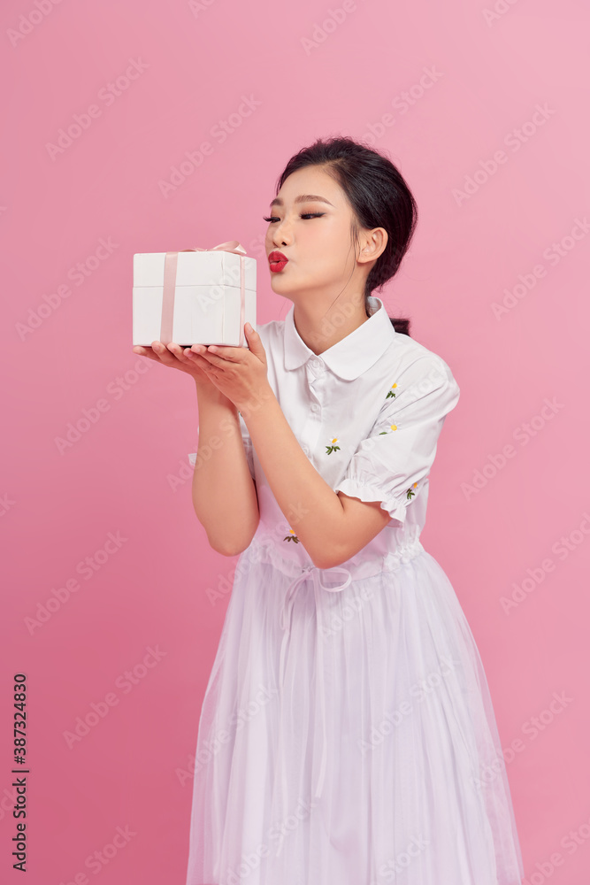 portrait of fascinating girl making kissing face expressing while holding big gift.