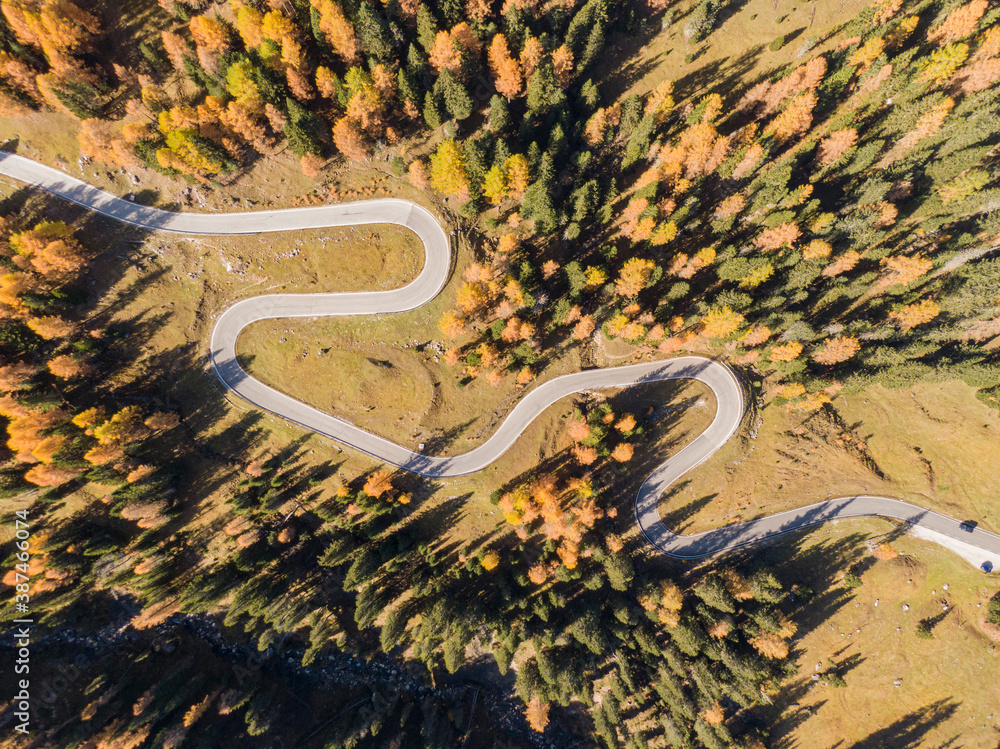 TOP DOWN: Lone white car cruises along the switchback road in the Dolomites.