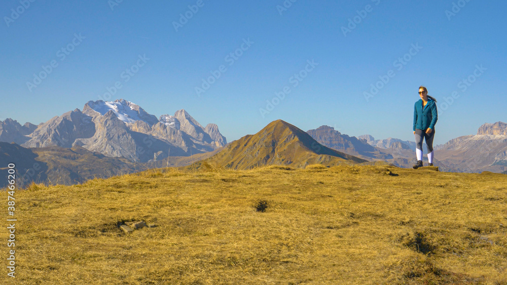 COPY SPACE: Cinematic shot of a female tourist hiking up a hill in Dolomites.