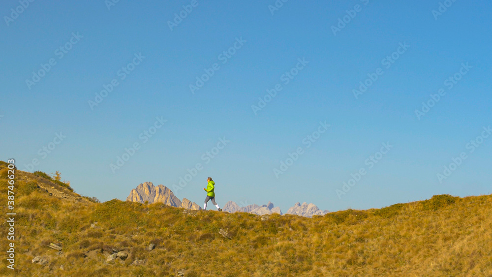 Young female hiker runs up an empty hiking trail in the picturesque Dolomites