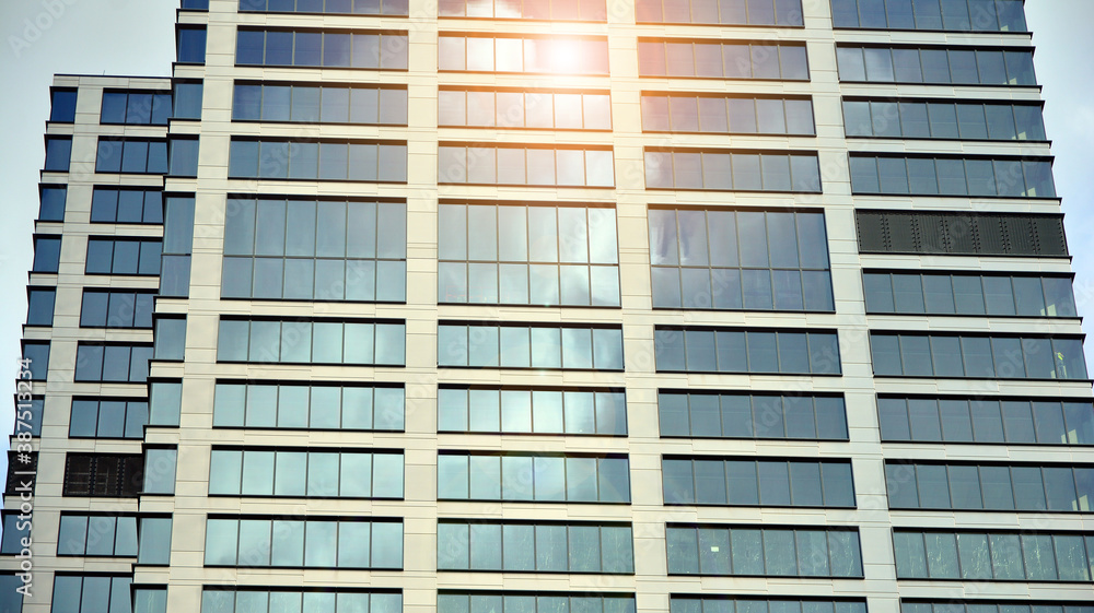 Blue curtain wall made of toned glass and steel constructions under blue sky. A fragment of a buildi