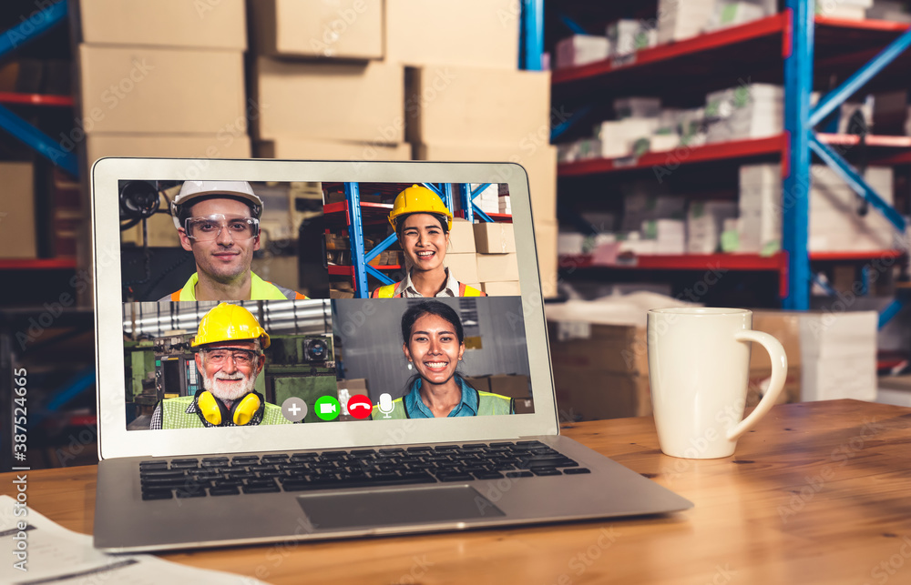 Warehouse staff talking on video call at computer screen in storage warehouse . Online software tech