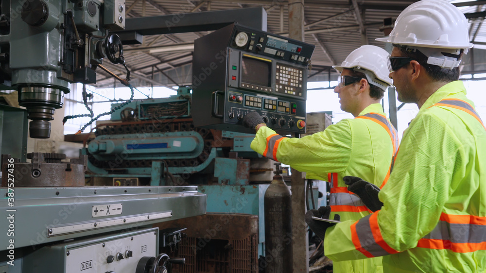 Group of factory workers using machine equipment in factory workshop . Industry and engineering conc