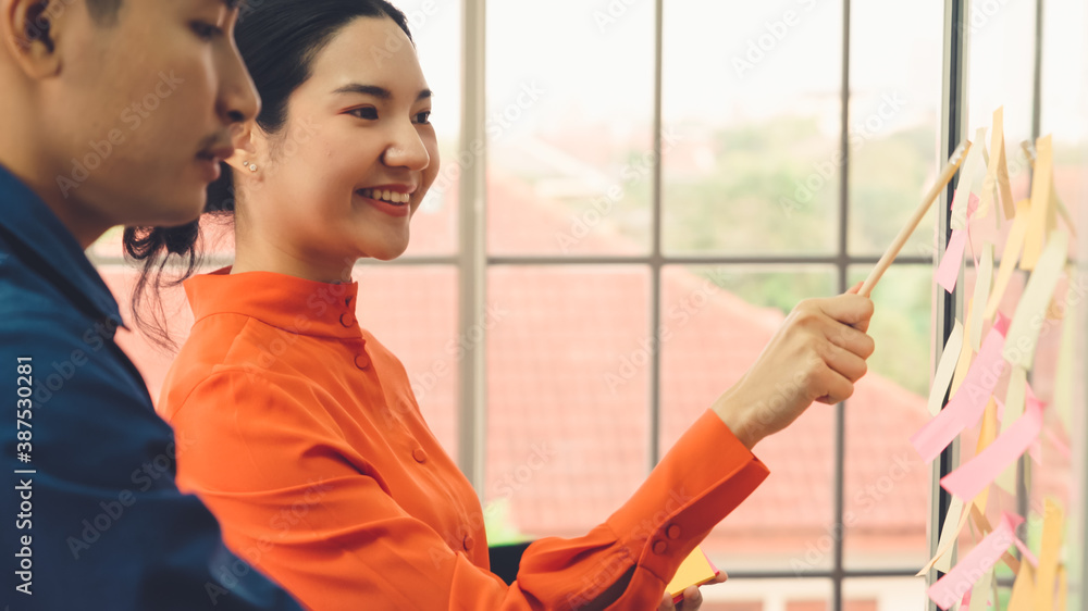 Business people work on project planning board in office and having conversation with coworker frien