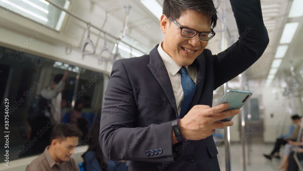 Businessman using mobile phone on public train . Urban city lifestyle commuting concept .