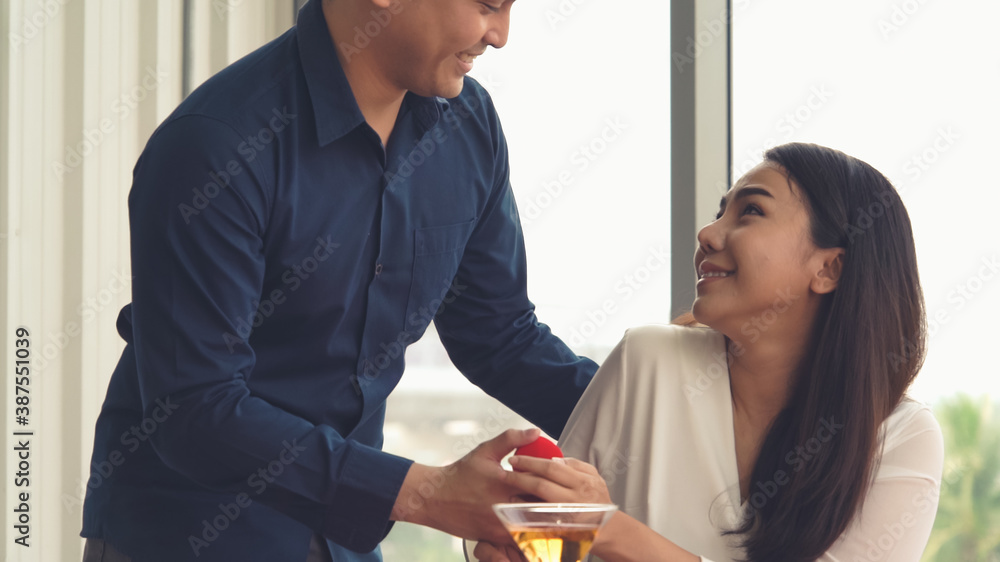 Romantic couple giving gift to lover at restaurant . Happy couple lifestyle .