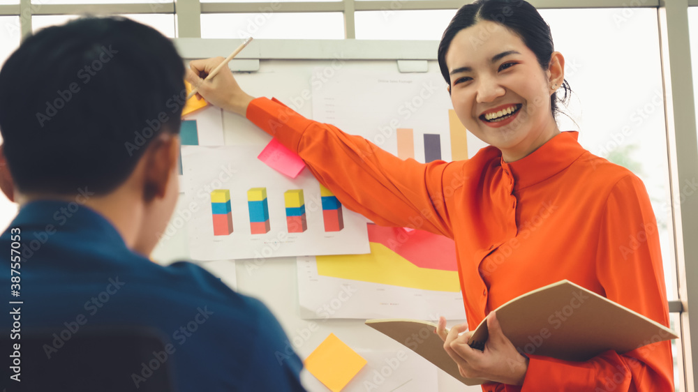 Young woman explains business data on white board in casual office room . The confident Asian busine