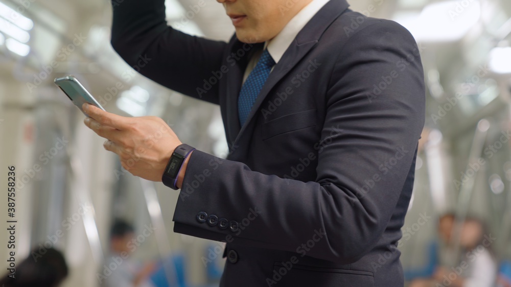 Businessman using mobile phone on public train . Urban city lifestyle commuting concept .