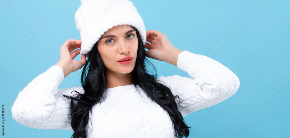 Young woman in a cold weather winter outfit on a blue background