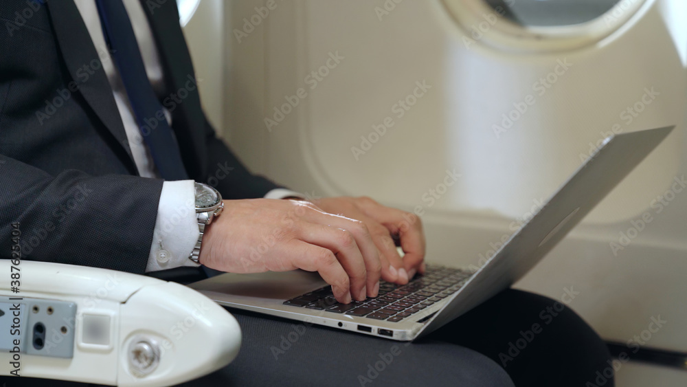 Young businessman using laptop computer in airplane . Business trip travel concept .