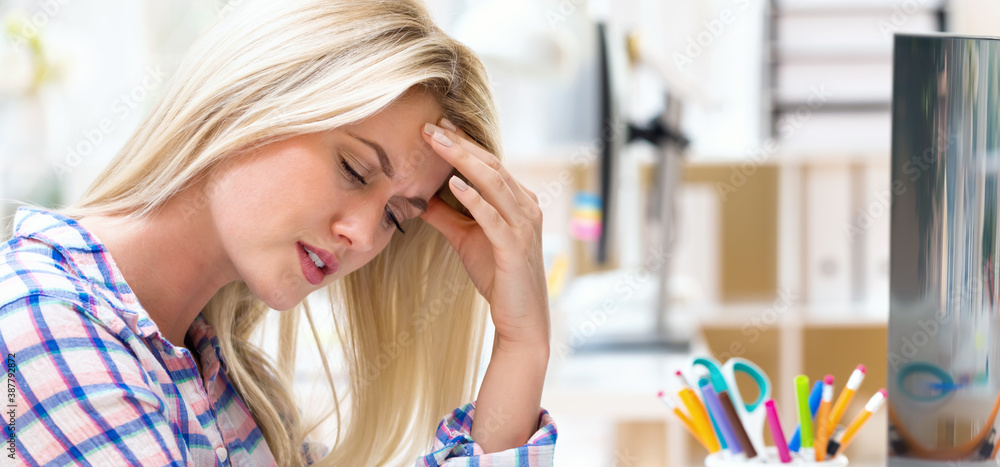 Young woman feeling stressed at her desk