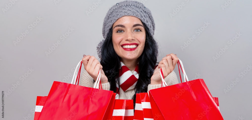 Happy young woman holding shopping bags on a gray background