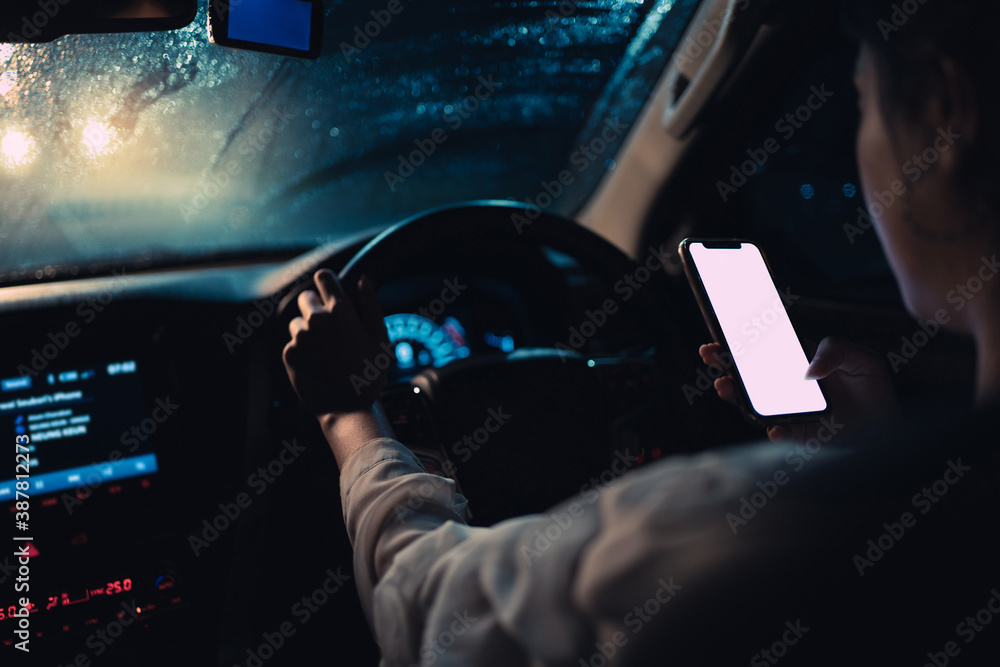 Asian woman is driving alone at night. Its raining. She using smart phone while driving