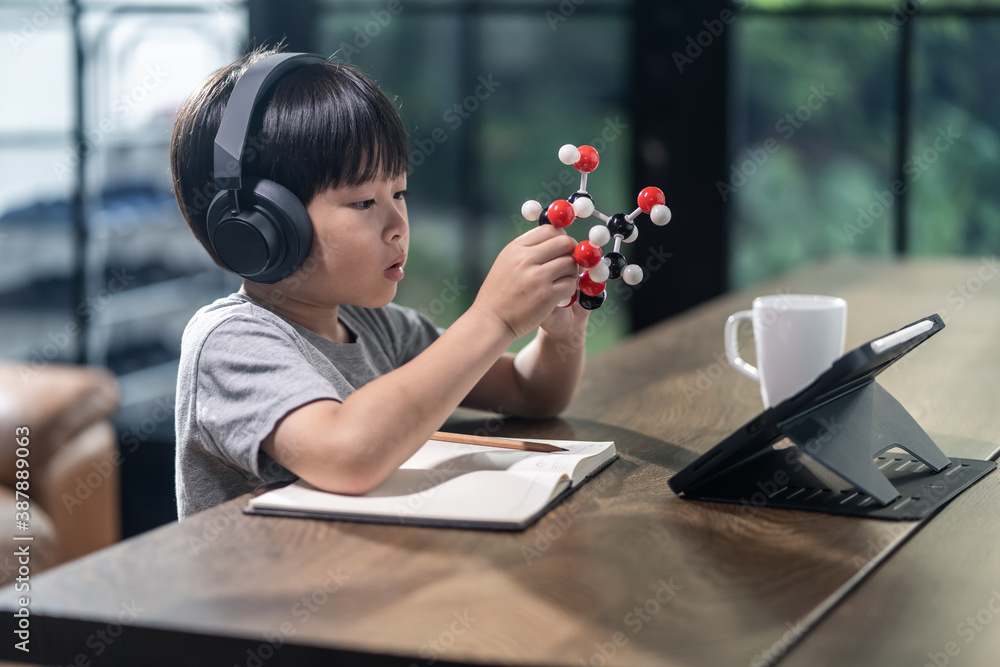 Asian little boy assembling molecular model by learning from home.