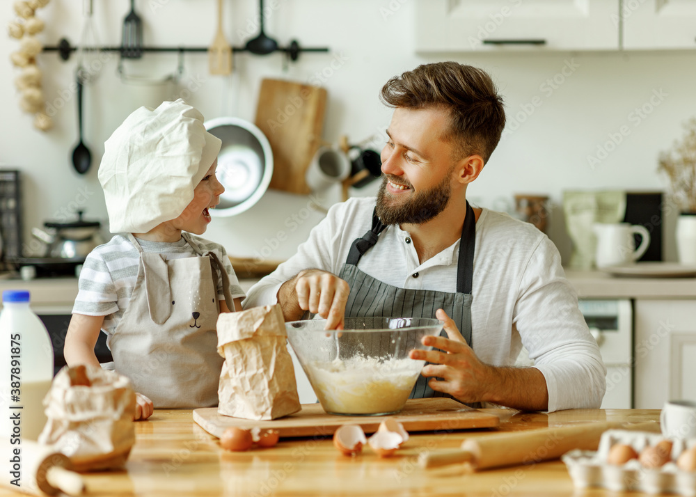 Happy man with kid preparing dough at home.