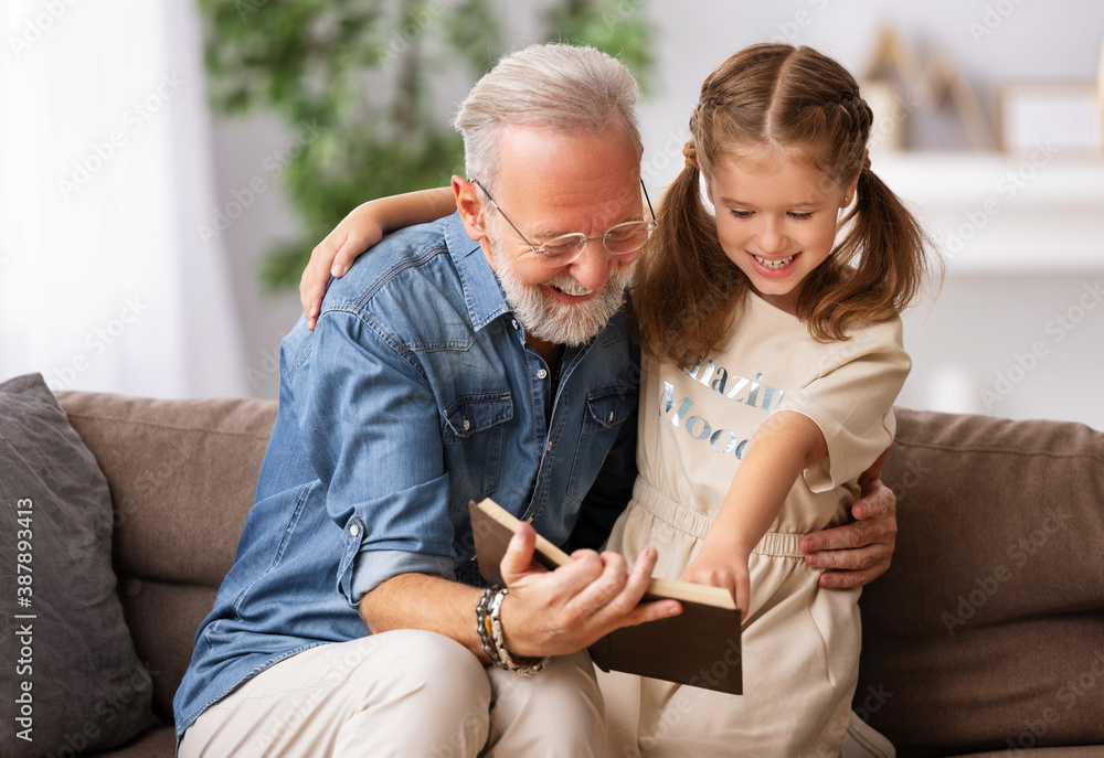 Happy grandfather reading book to granddaughter.