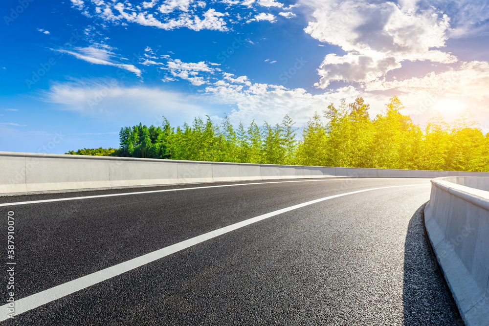 Asphalt road and green bamboo with mountain natural scenery in Hangzhou on a sunny day.