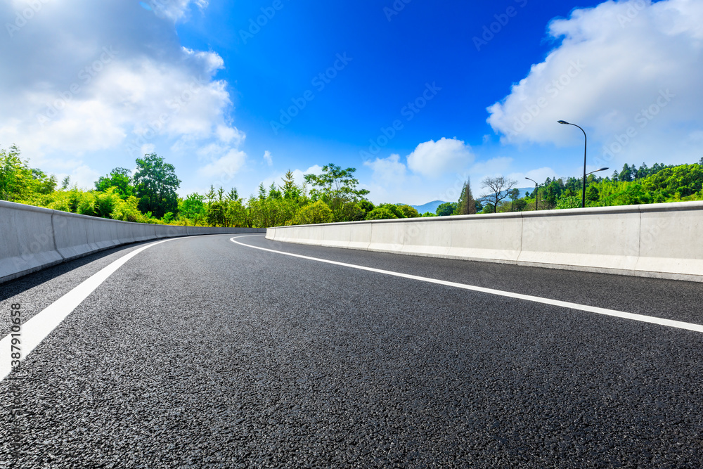 Asphalt road and green plants with mountain natural scenery in Hangzhou on a sunny day.