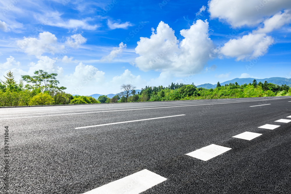 Asphalt road and green plants with mountain natural scenery in Hangzhou on a sunny day.