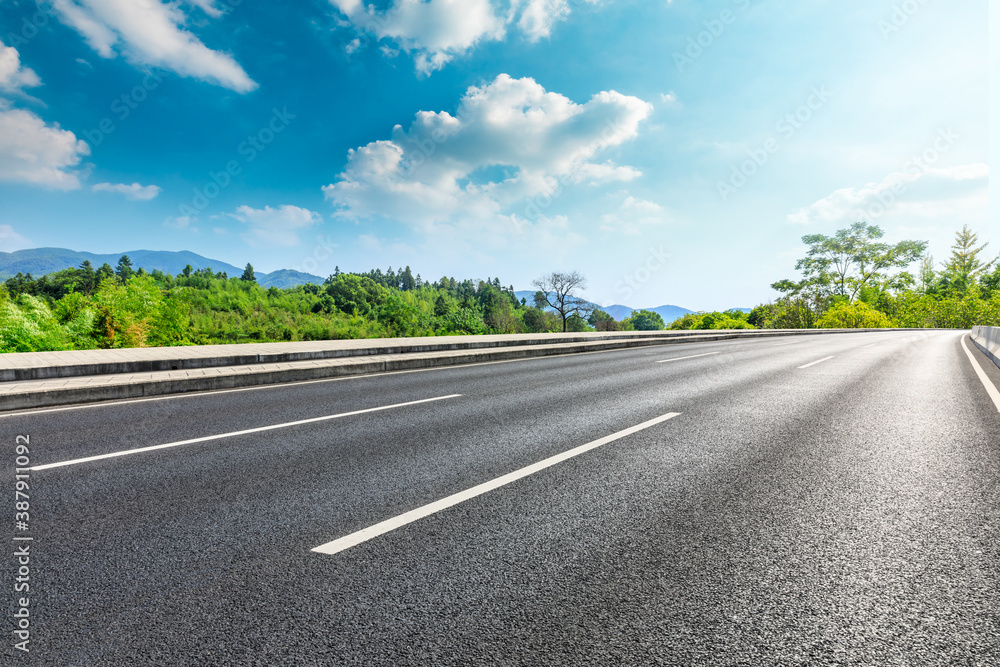 Asphalt road and green plants with mountain natural scenery in Hangzhou on a sunny day.