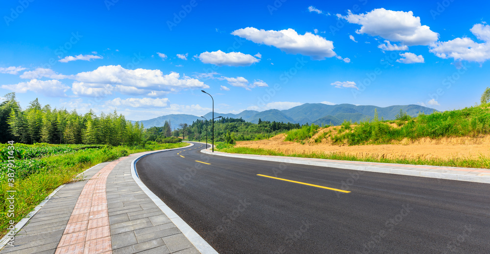 Countryside asphalt road and green plants with mountain natural scenery in Hangzhou on a sunny day.