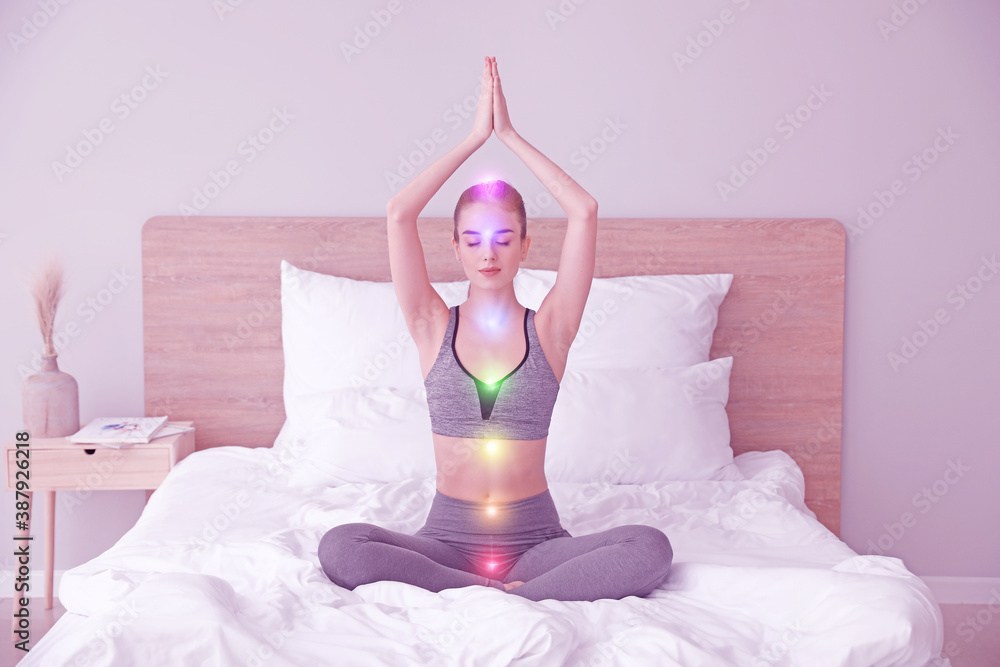 Beautiful young woman practicing yoga in bedroom