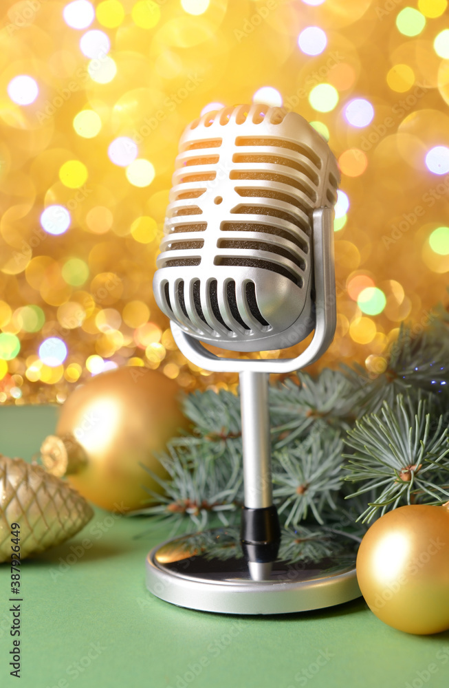 Retro microphone with Christmas decor on table against blurred lights