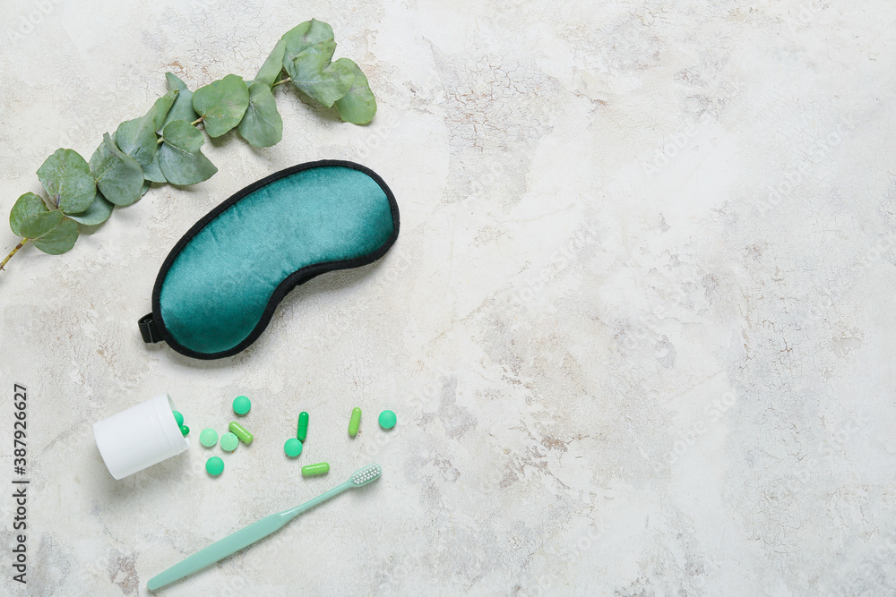 Sleeping mask, tooth brush and pills on light background