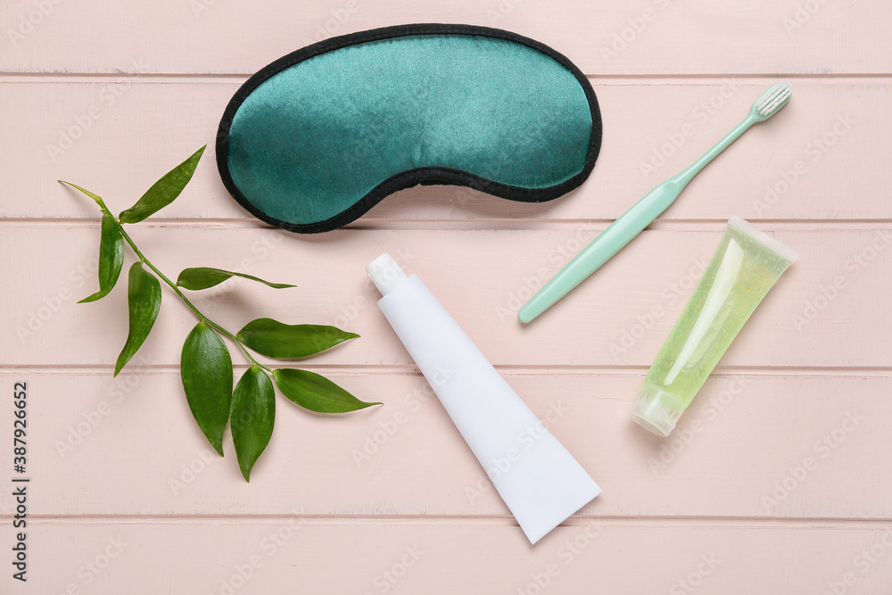 Tooth brush, paste and sleeping mask on wooden background