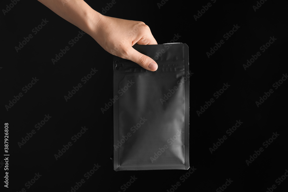 Hand with coffee bag on dark background