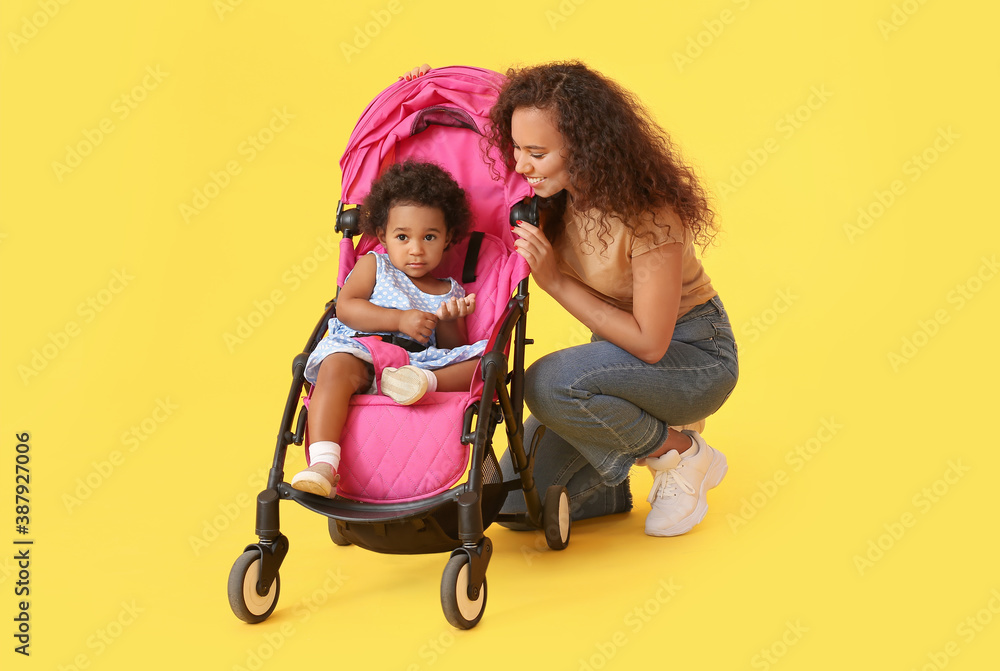 African-American woman and her cute baby in stroller on color background