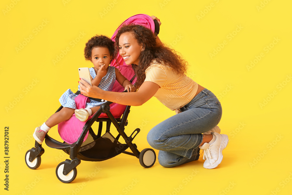 African-American woman and her cute baby in stroller on color background