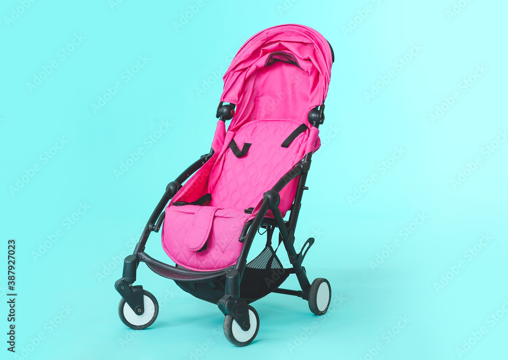 Modern baby stroller on color background