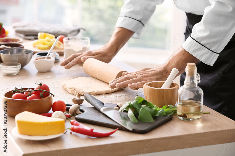 Mature male chef making dough for pizza in kitchen