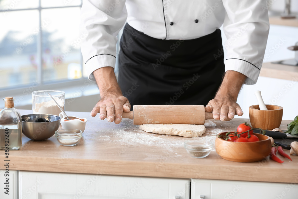 Mature male chef making dough for pizza in kitchen