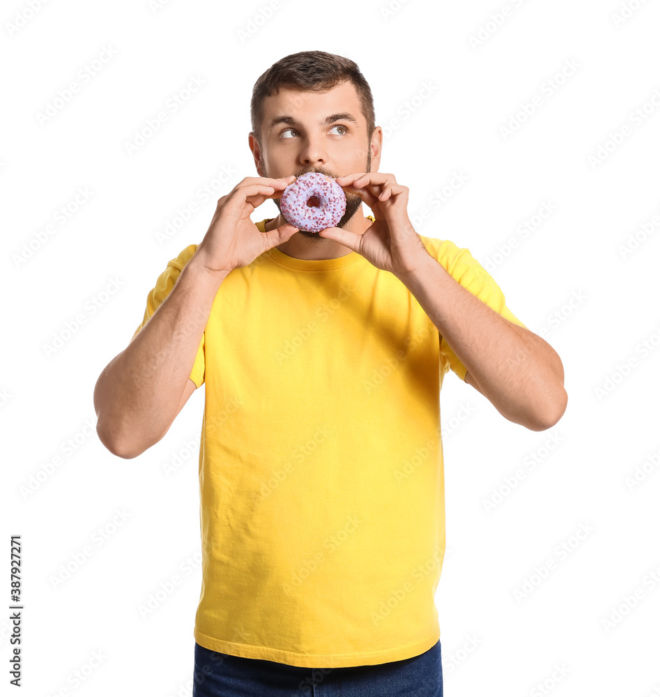 Handsome young man with sweet donut on white background