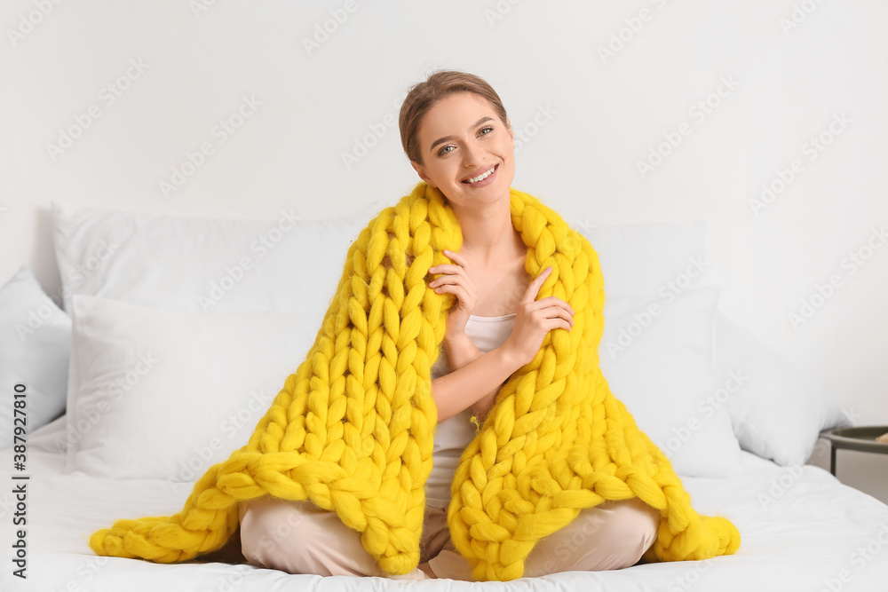 Happy young woman with warm plaid at home