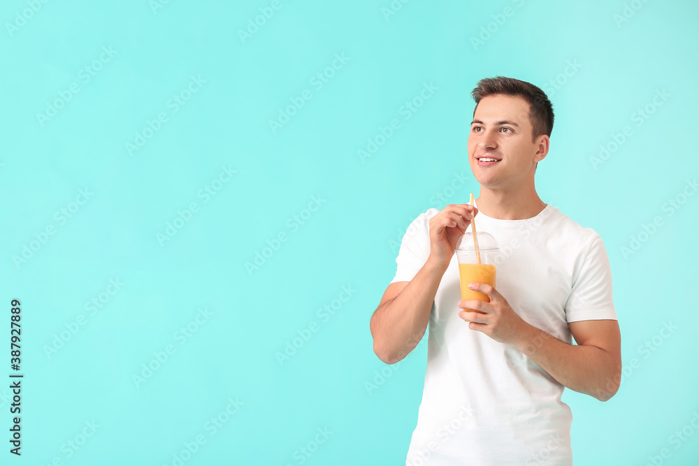 Handsome man with orange juice on color background