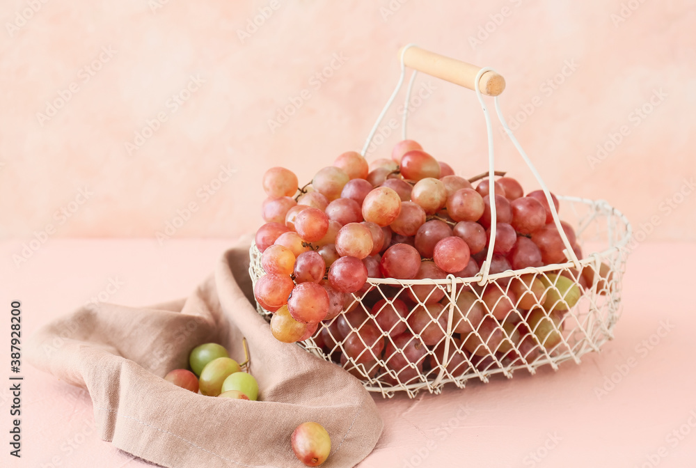 Basket with sweet ripe grapes on color background