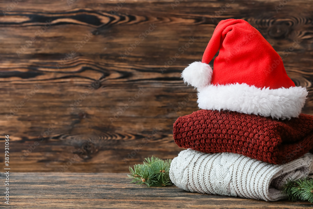 Stylish Christmas clothes with Santa Claus hat on table