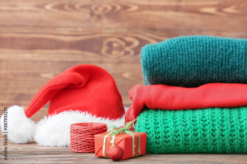 Stylish Christmas clothes with Santa Claus hat on table