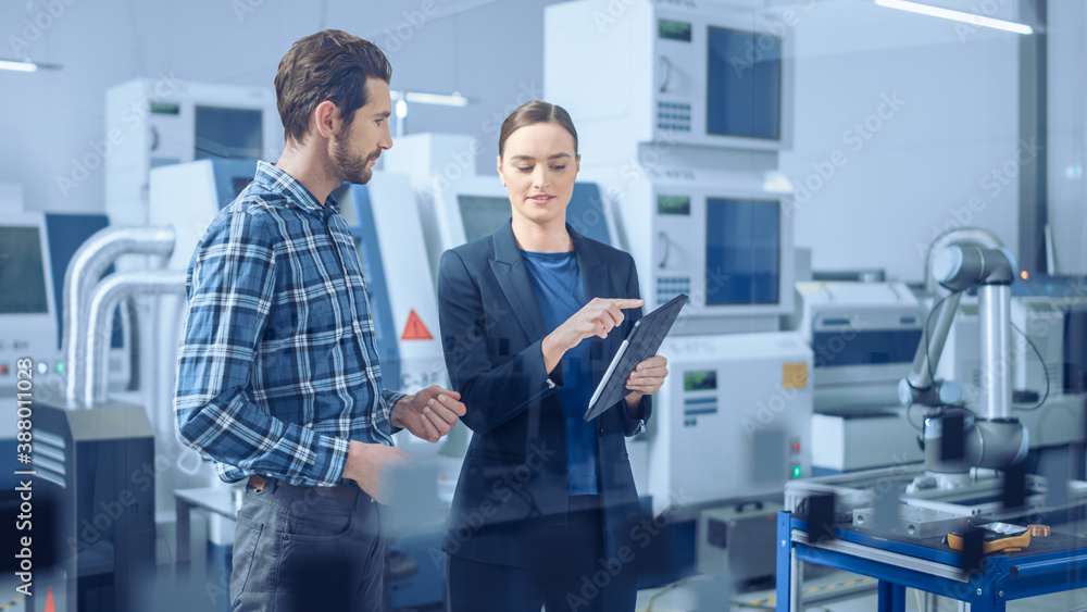 Modern Factory: Female Project Manager and Male Engineer Standing, Talking, Using Digital Tablet for