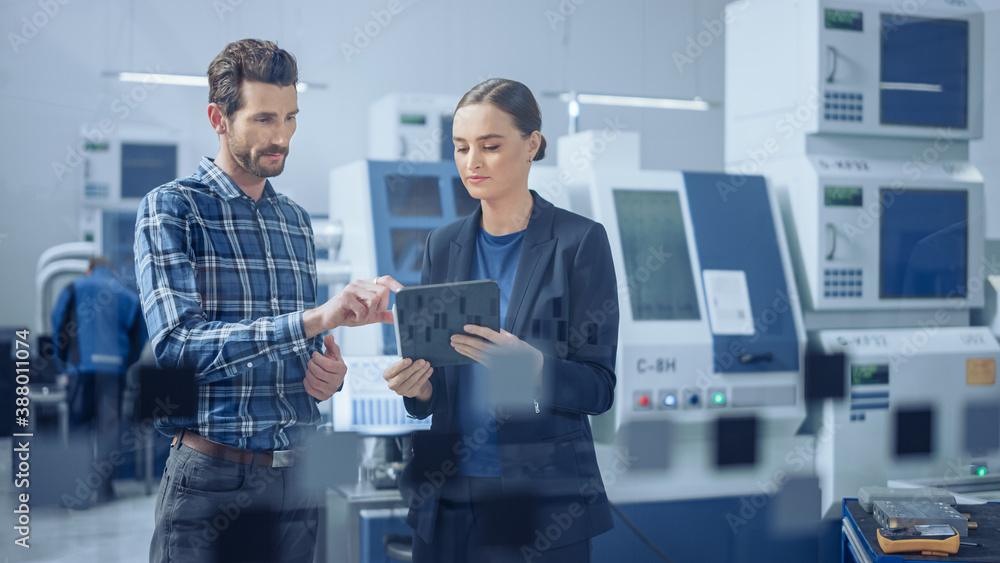 Modern Factory: Female Project Manager, Male Engineer Standing, Talking, Using Digital Tablet for Pr